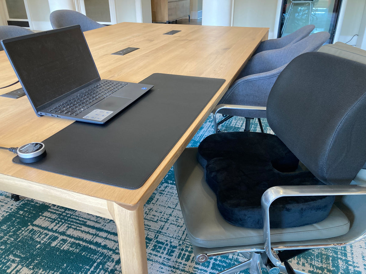 Conference room setup with a laptop on a table, chairs, and a rug.